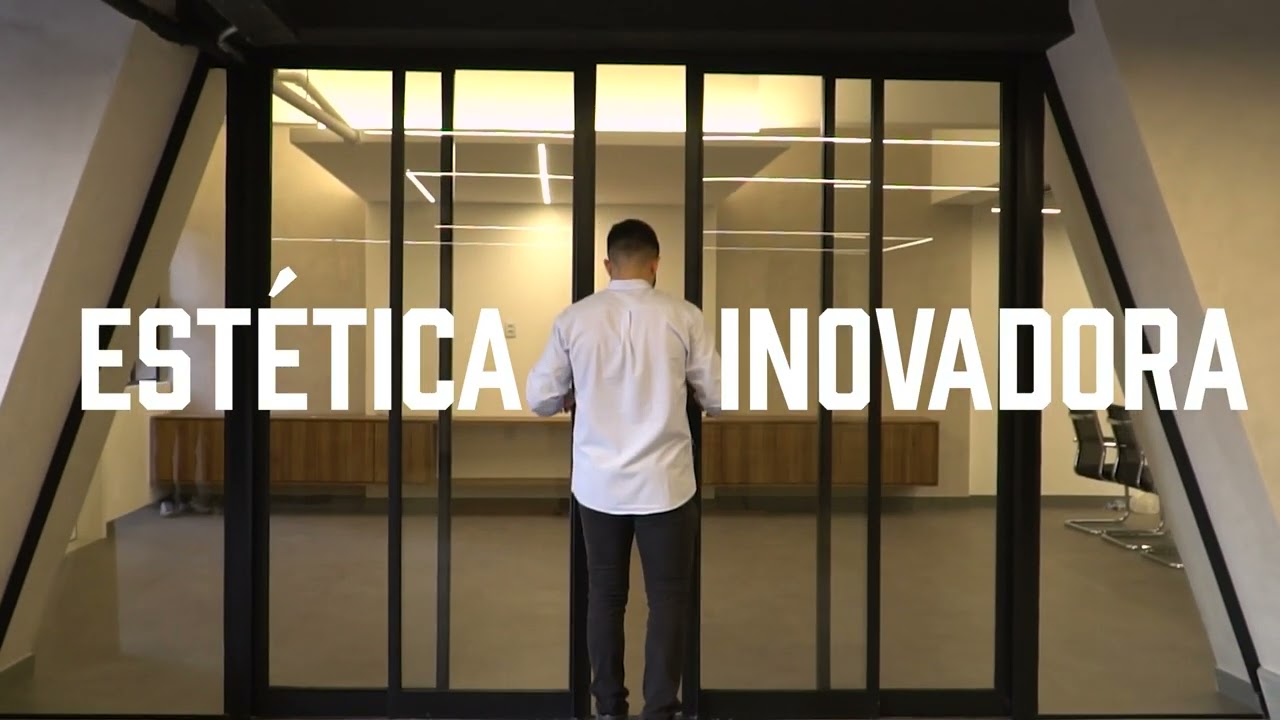 Recepção de escritório concluída após retrofit, com divisórias de vidro em perfil metálico preto e balcão em madeira